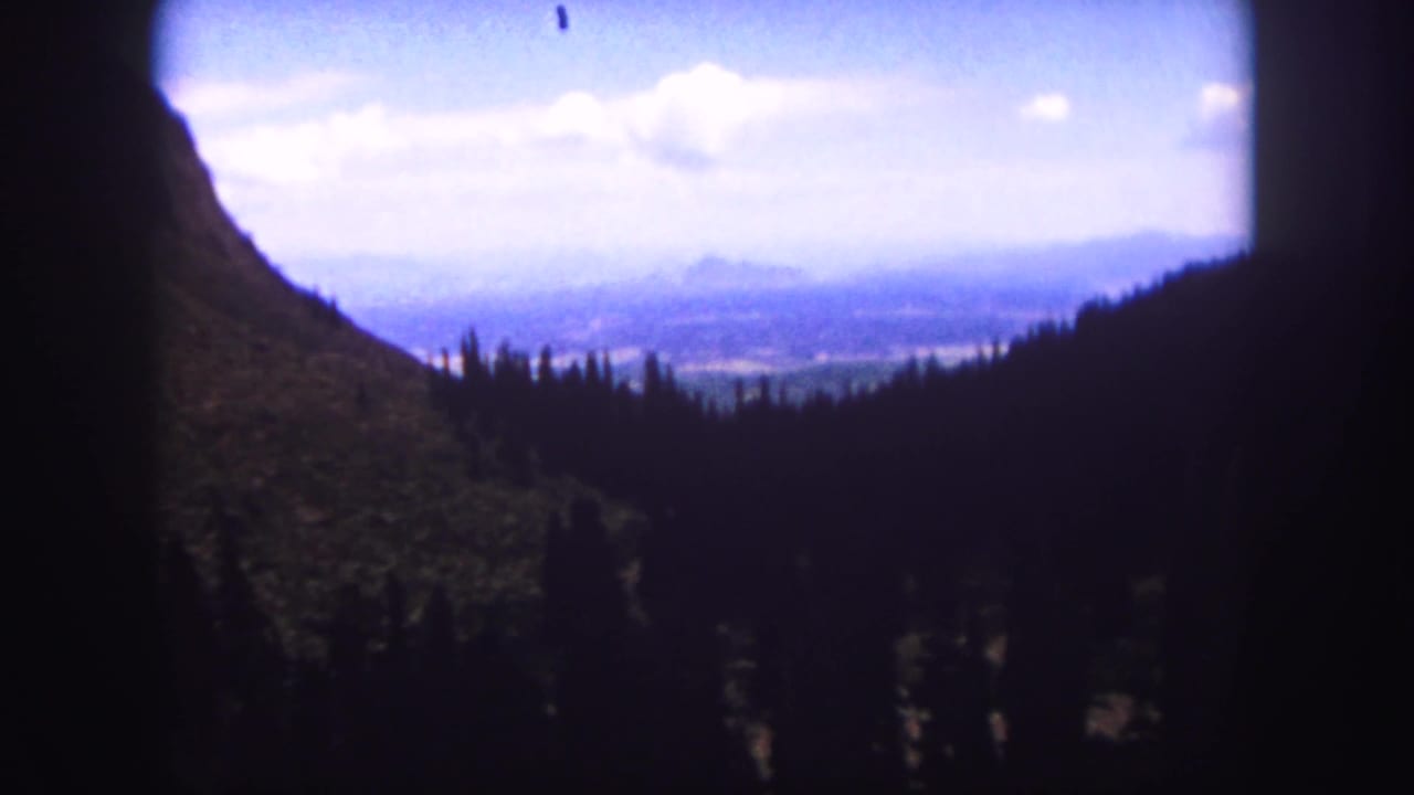 Mountain slope framing a distant valley under a blue sky.