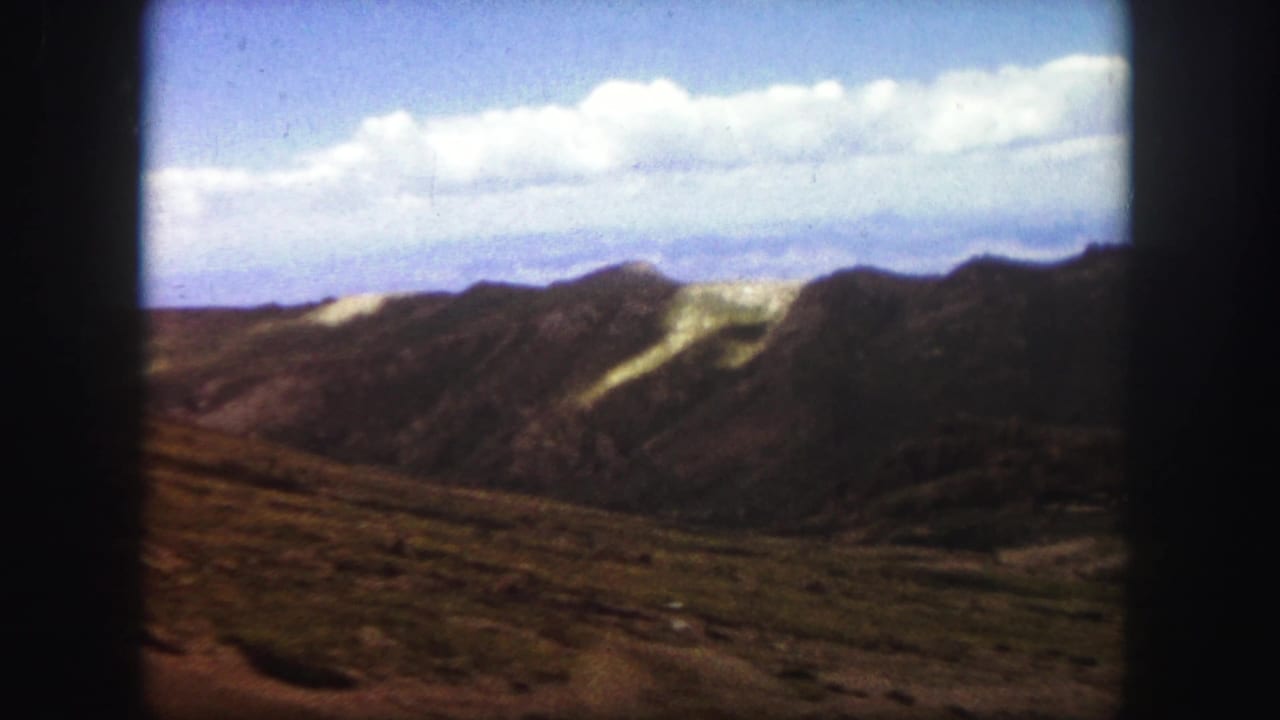 Distant rocky ridges under a blue sky with scattered clouds.