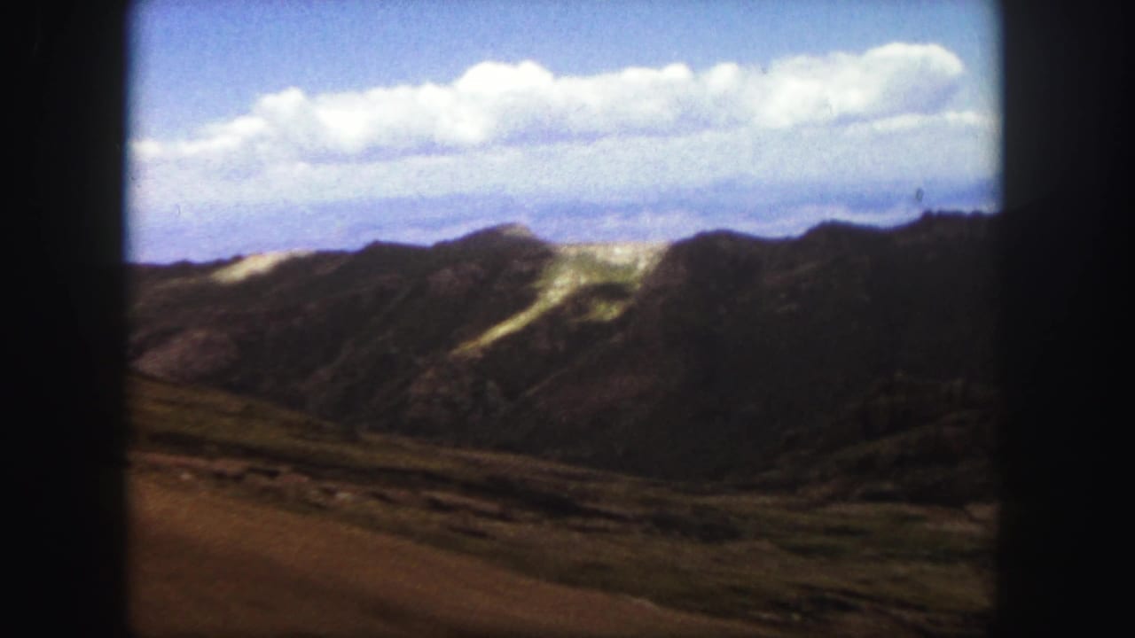 Mountain ridge line and open rocky terrain beneath a wide strip of white clouds.