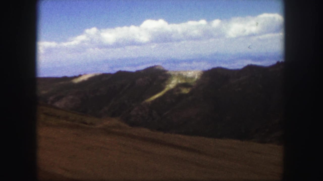1958 Colorado Springs home-movie view of rugged hills and clouded blue sky from a scenic mountain drive.