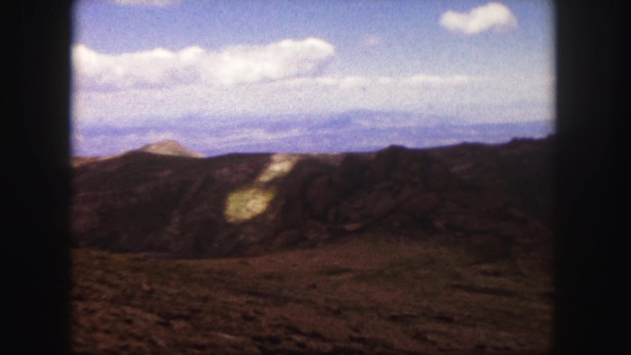 1958 Colorado Springs home-movie view of rocky hills and distant mountains beneath scattered clouds.