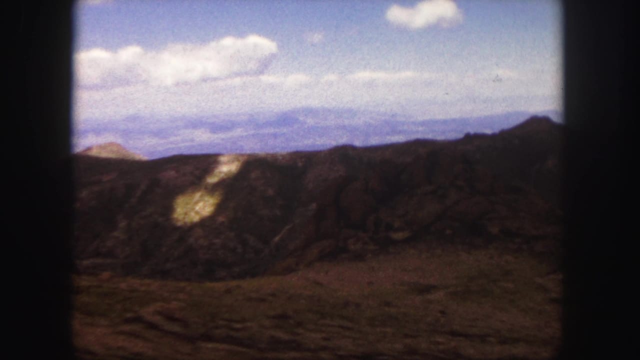 Rugged hillside and distant mountain horizon seen through dark 8mm frame edges.
