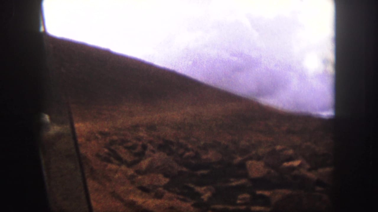 Rocky hillside near Colorado Springs with a dusty unpaved road partly visible, filmed in soft 8mm color.