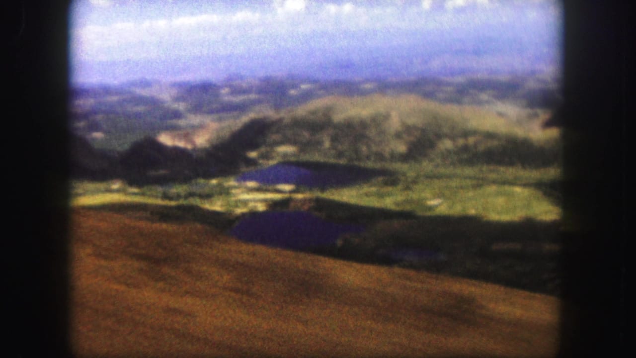 High overlook across rolling hills, small lakes, and a hazy distant landscape.