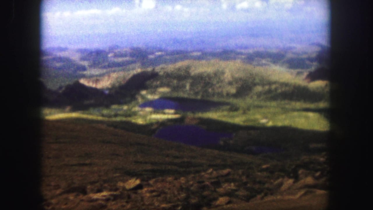 Similar mountain panorama with lakes and rolling ridges seen through soft film framing.