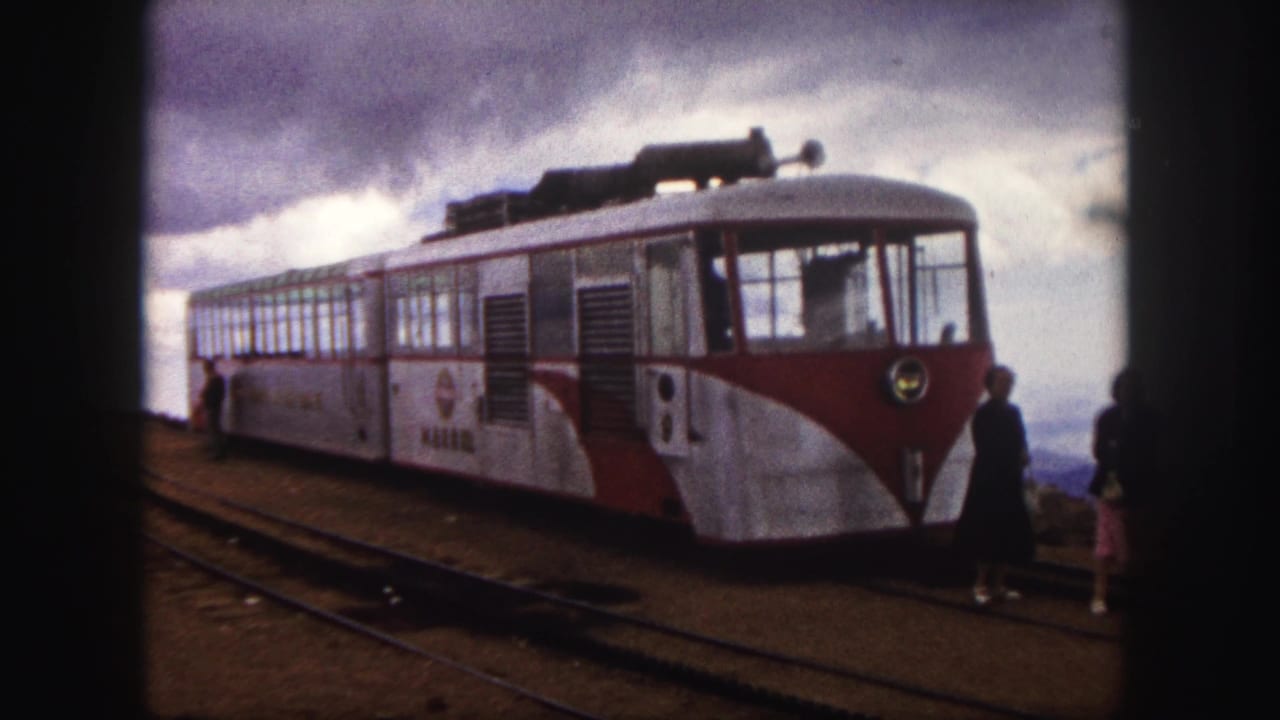 Colorado Springs 1958 frame of a red-and-white mountain train at the station, with passengers near the front and rails in the foreground.