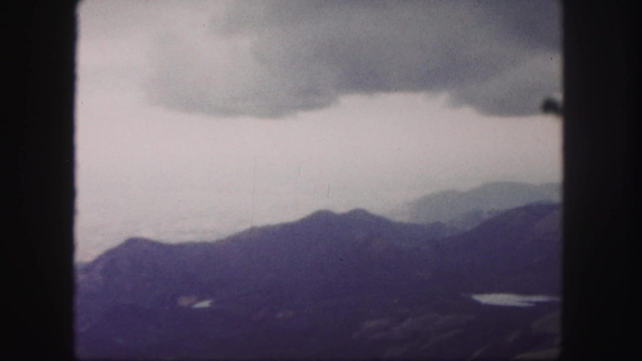 Scenic 1958 Colorado Springs home-movie frame focused on layered mountains and overcast sky.