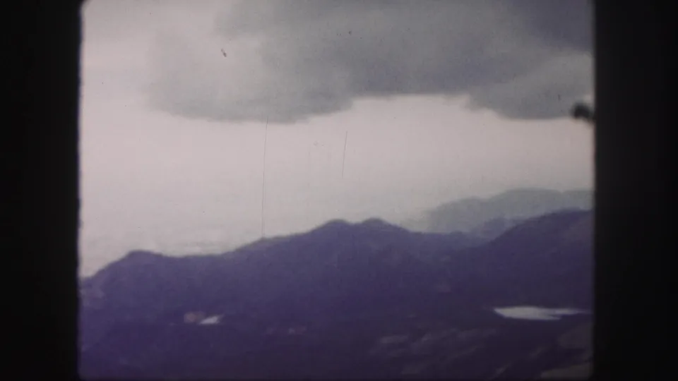 Colorado Springs mountain vista on 8mm film, showing distant ridges under a broad cloudy sky.