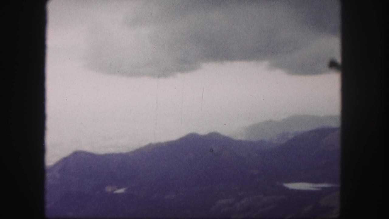 Hazy mountain ridges below a cloudy sky, with dark 8mm frame borders.