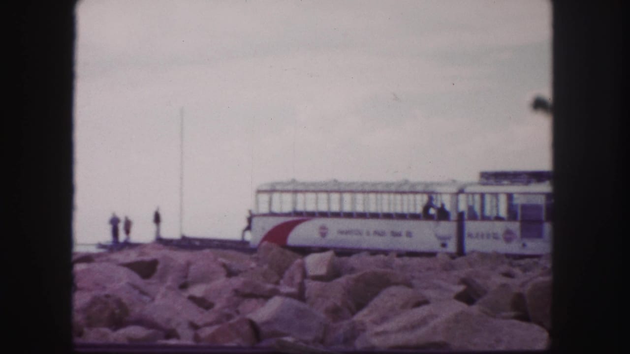 Pikes Peak summit railway scene in 1958 home-movie footage, showing the train car, rocks, and distant visitors.