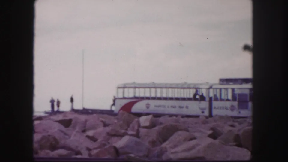 Pikes Peak summit railway scene in 1958 home-movie footage, showing the train car, rocks, and distant visitors.