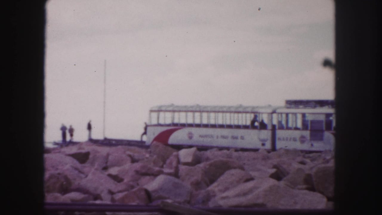 A red and white Pikes Peak Cog Railway car appears at a rocky overlook in 1958 Colorado Springs home-movie footage.