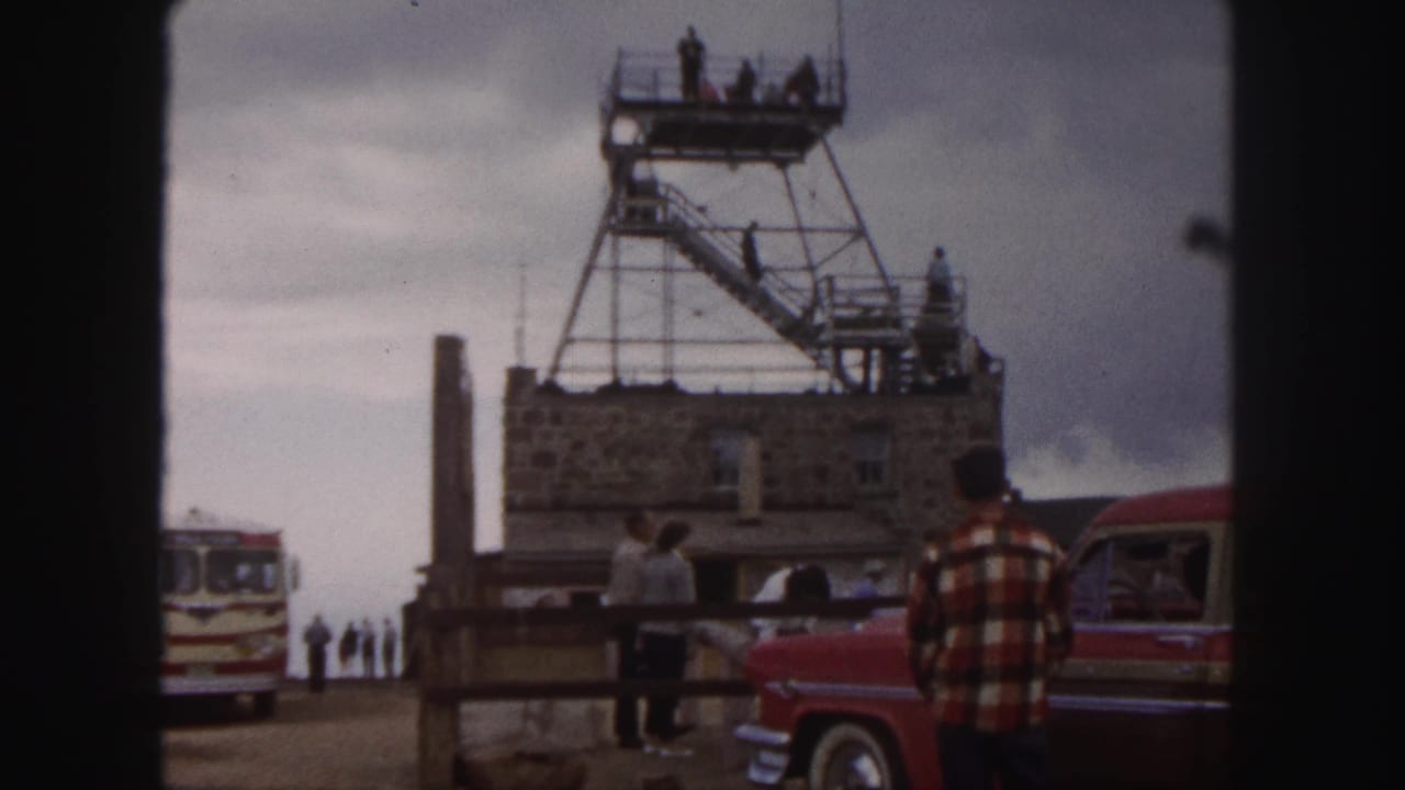 Colorado Springs tourist overlook in 1958, with people on a tower platform, a red car at right, and a striped bus at left.