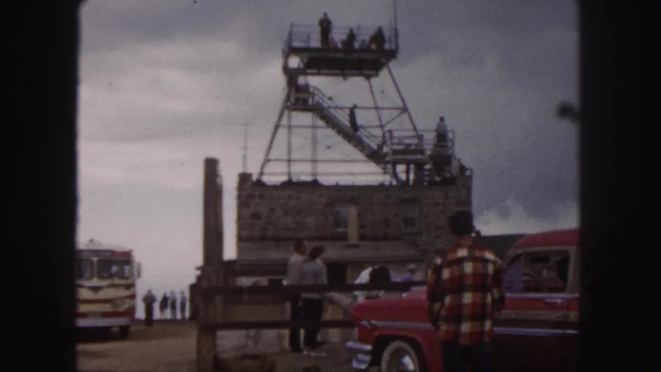 Colorado Springs tourist overlook in 1958, with people on a tower platform, a red car at right, and a striped bus at left.