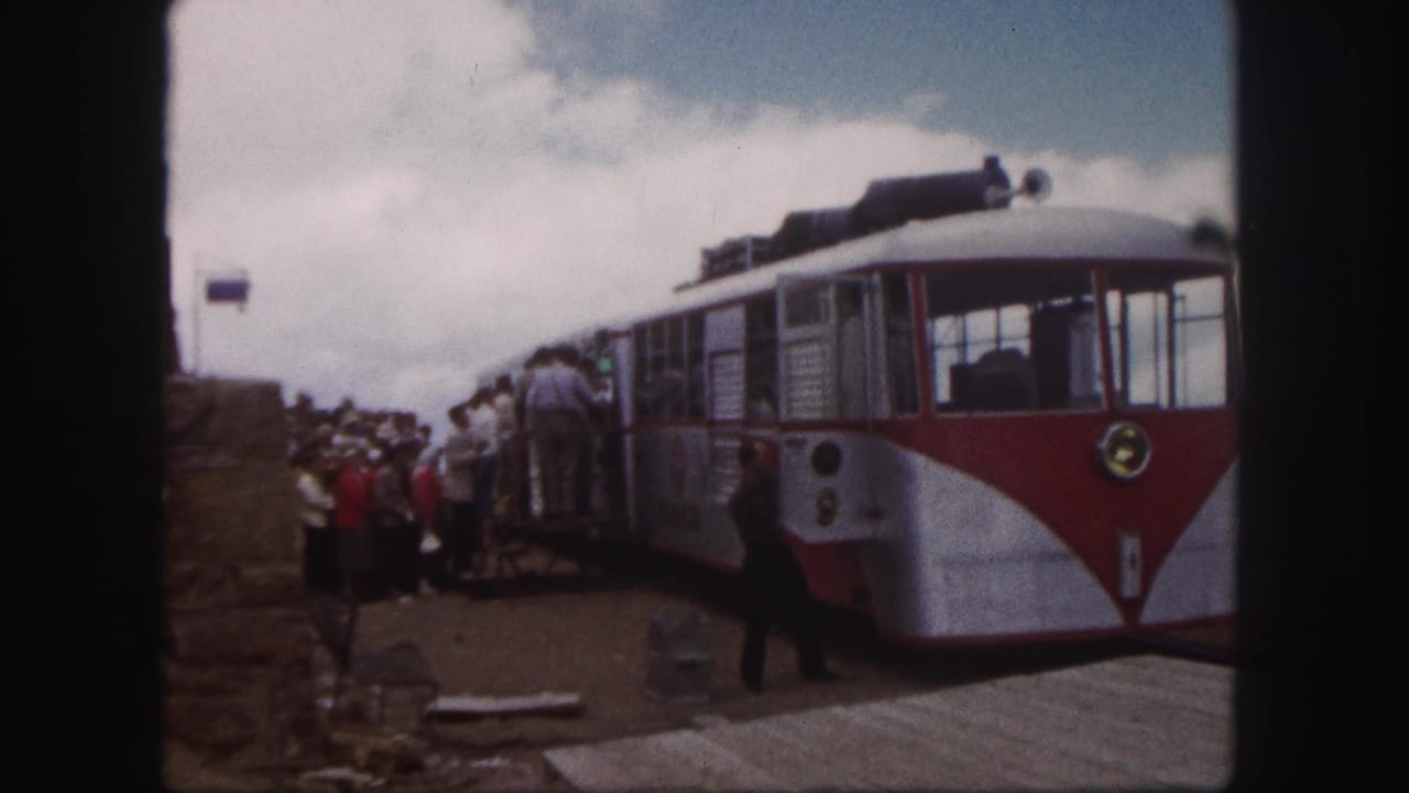 1958 Colorado Springs home-movie view of tourists waiting by a red and white mountain transport car as one person crosses the platform.