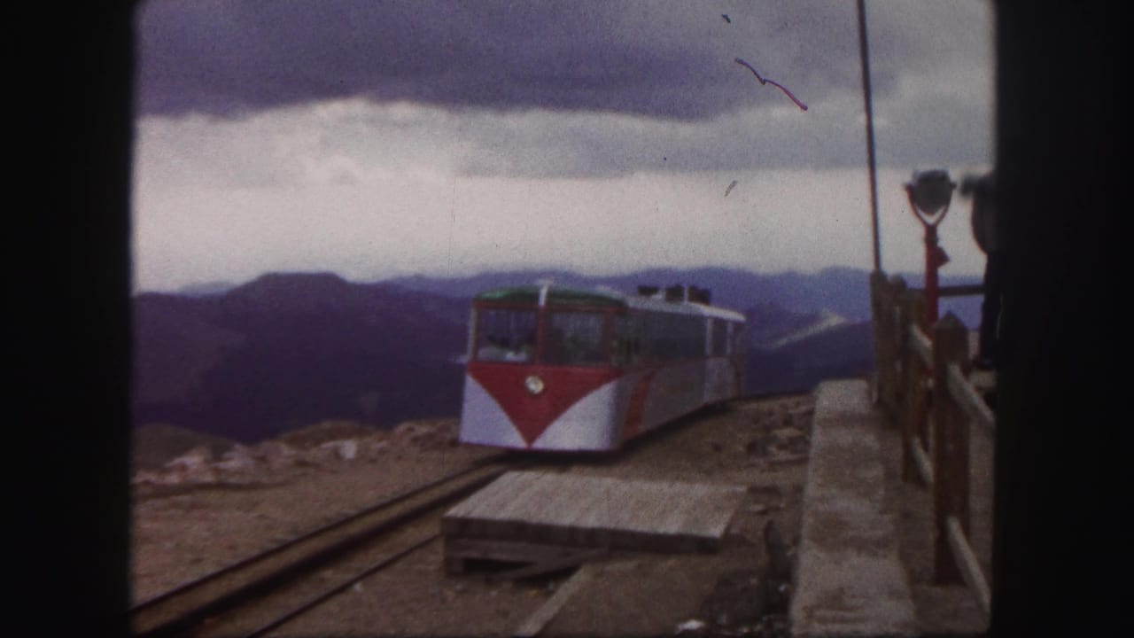 1958 Colorado Springs frame showing the railcar farther from the camera on station tracks, with platform boards and mountains visible.