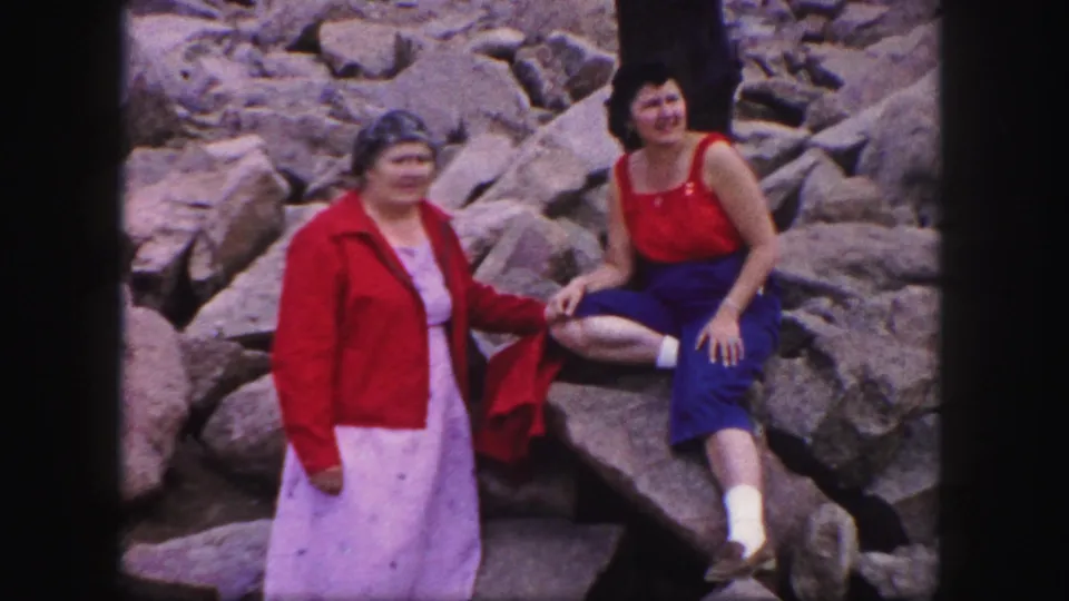 At the end of the 1958 Colorado Springs clip, two adult women smile on rocks, combining posed portrait framing with casual home-movie movement.