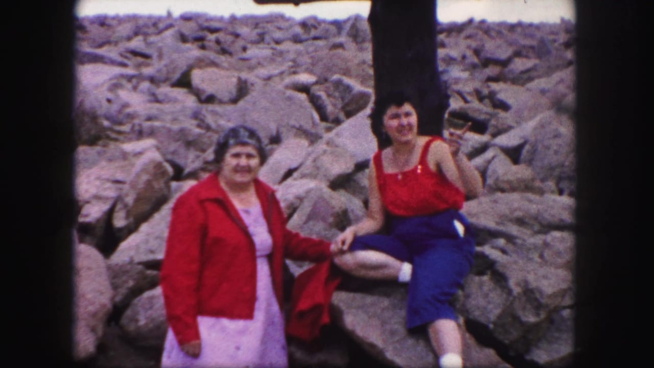 Two women in red clothing pose on the rocky Pikes Peak summit in 1958 home-movie footage.