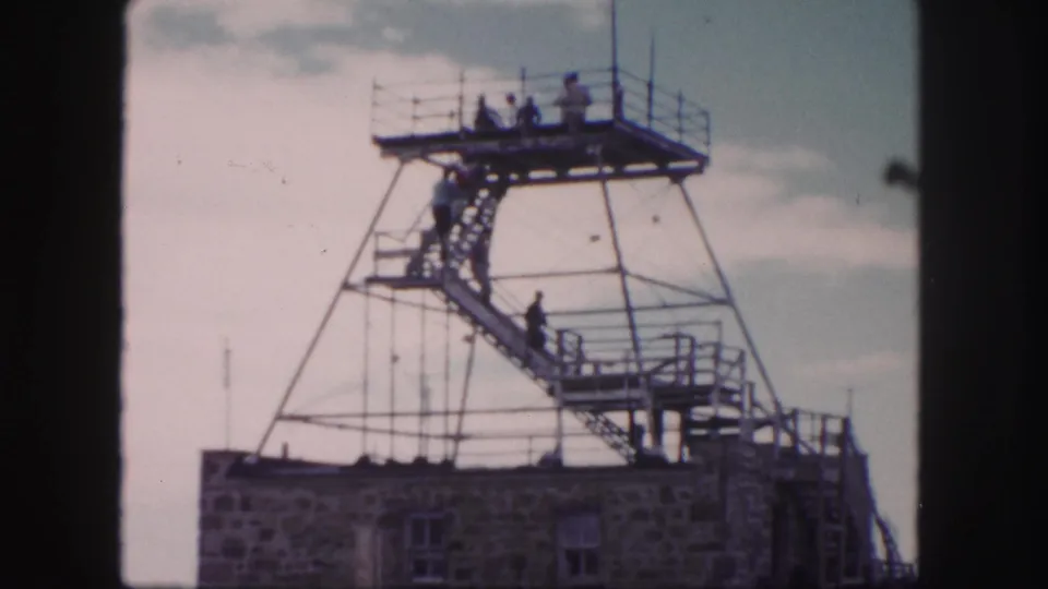 People climb and stand on a steel observation tower, seen from below in 1958 Colorado Springs home-movie footage.