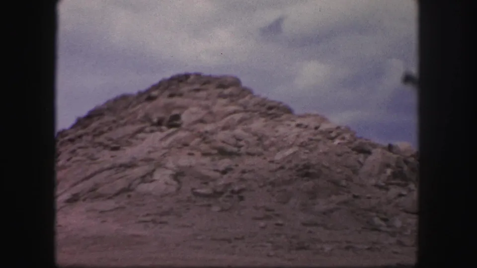 Rocky Colorado Springs terrain appears through the moving vehicle window in this 1958 8mm frame.