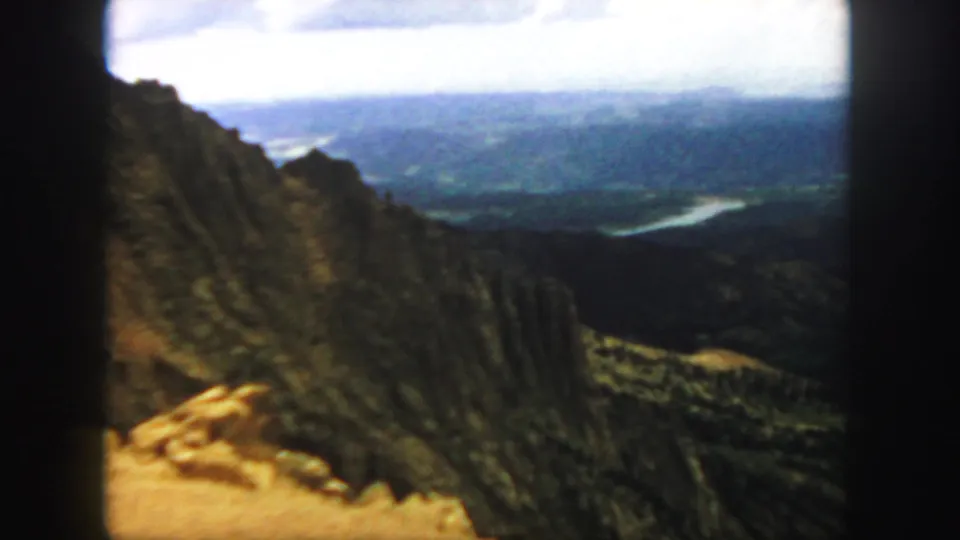 1958 Colorado 8mm frame showing a canyon ridge and distant winding river across a broad mountain valley.