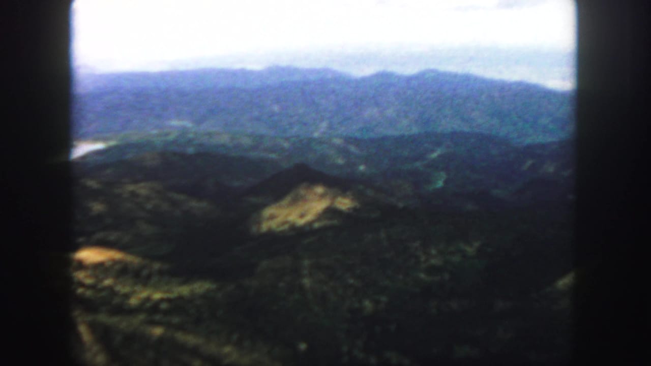 Colorado mountain ridges in soft blue tones, filmed on 8mm with dark frame edges and a bright sky.