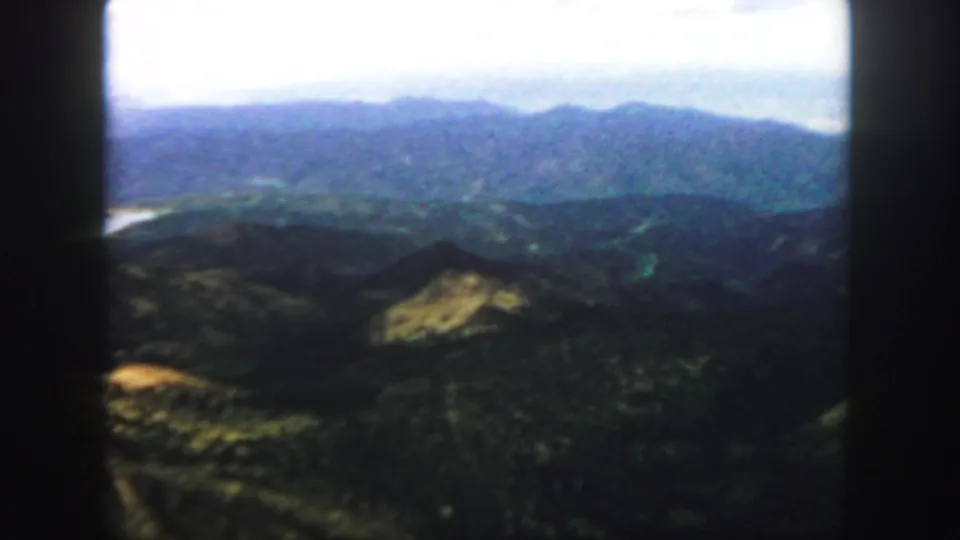 Colorado mountain ridges in soft blue tones, filmed on 8mm with dark frame edges and a bright sky.