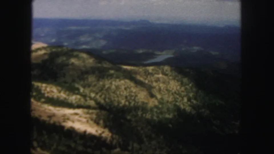 Colorado 1958 8mm frame looking over textured mountain ridges toward a hazy valley below.
