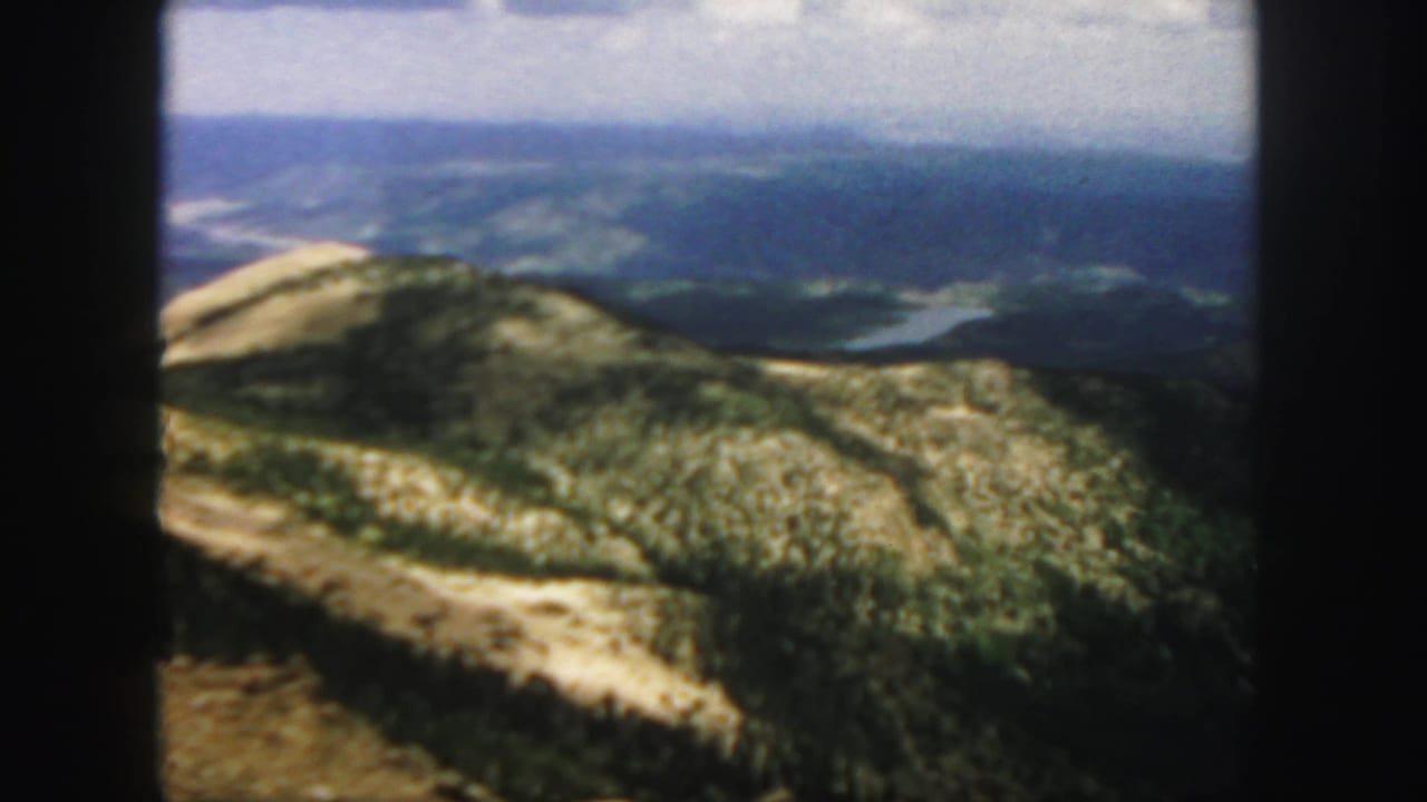 Mountain ridges and distant water seen through dark 8mm frame borders.
