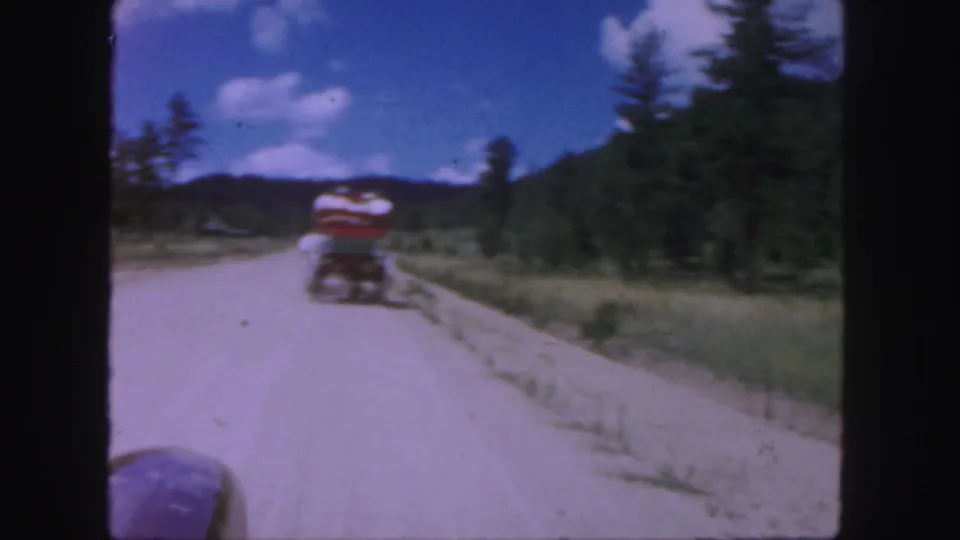 Horse-drawn wagon seen ahead on a rural Colorado road under a blue sky in 1958 home-movie footage.