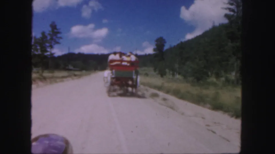 Final 1958 Colorado frame shows the red-and-white cart still moving away along the unpaved road through a green mountain landscape.