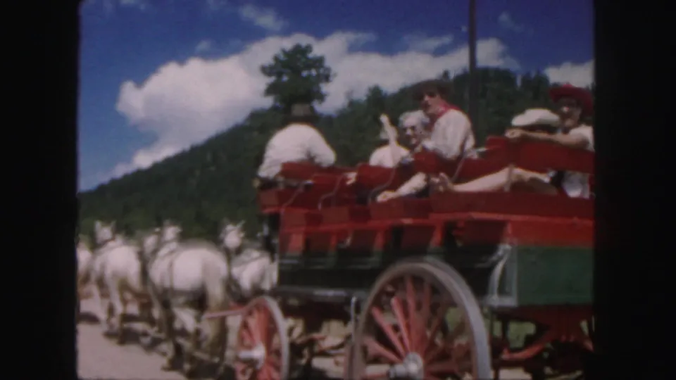1958 Colorado 8mm frame with a closer view of tourists seated in a red horse-drawn carriage pulled by white horses.