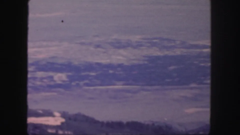 1958 Colorado 8mm view of hazy mountain ridges and open valley terrain with purple color fading.