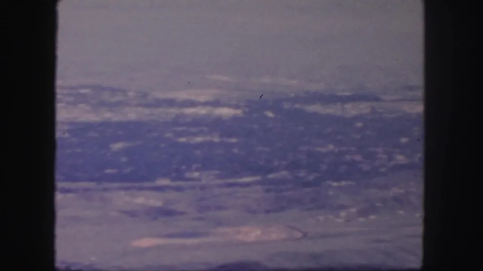1958 Colorado 8mm frame with distant ridges, valley floor, pale haze, and visible film grain.