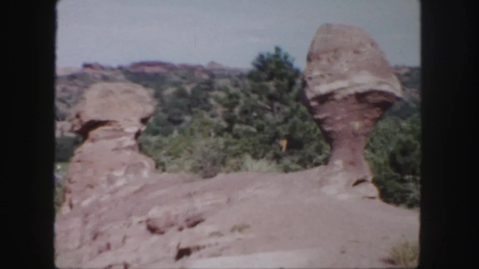 1958 Colorado frame with soft 8mm detail on two red rock formations and surrounding vegetation.