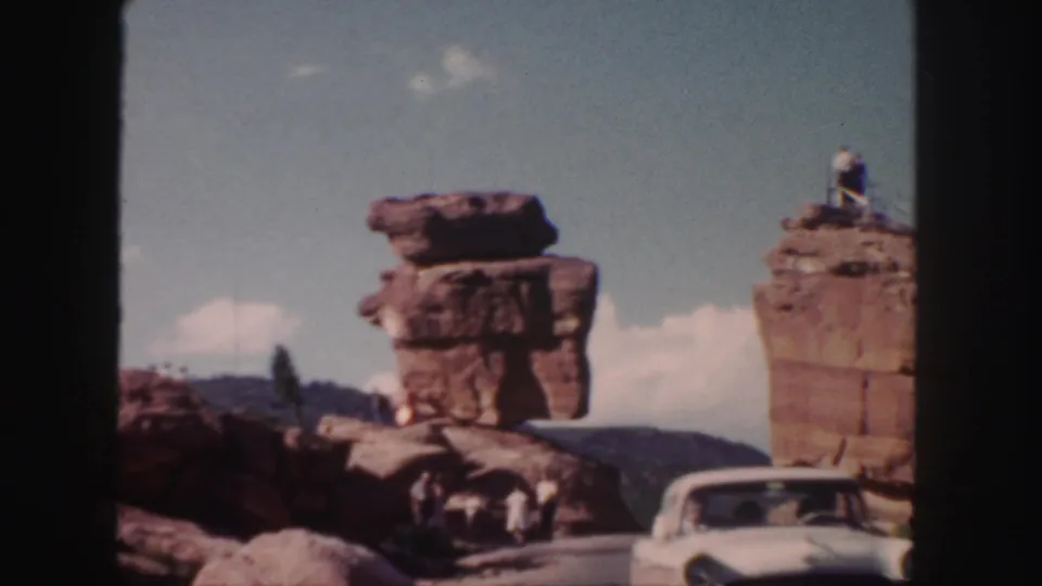 1958 Colorado travel frame with a white vintage car near sandstone formations and visitors positioned around the rocks.