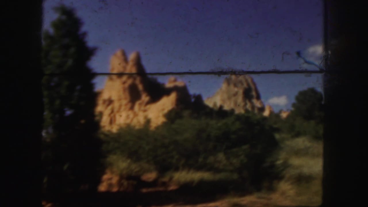 Golden rock formations and trees seen through dark car-window framing.