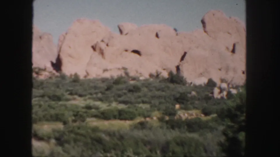 1958 Colorado scenic frame showing a broad sandstone ridge above scrubland, with no people or structures visible.