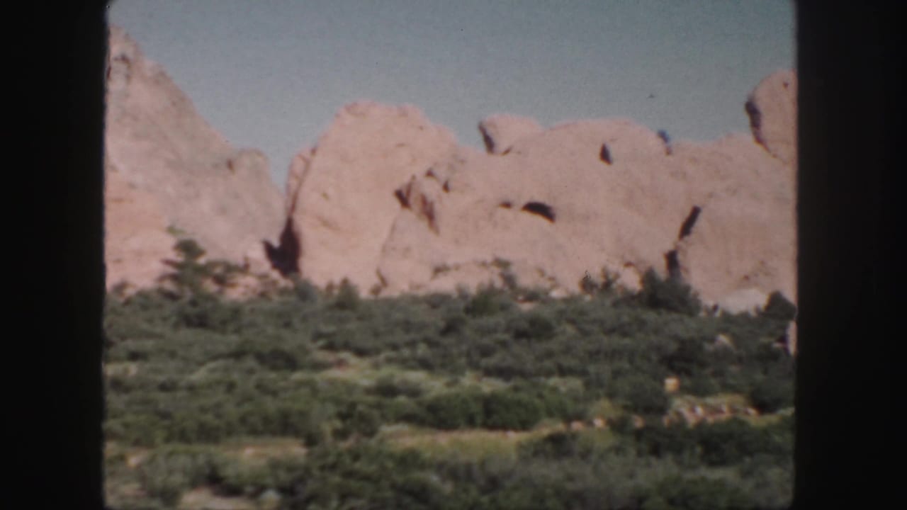 Sandstone ridge and green vegetation seen through vertical dark film borders.