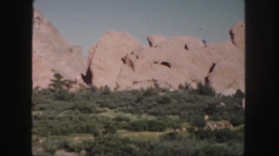 Colorado home-movie view of pink rock formations and scrub vegetation, with prominent 8mm frame borders visible.