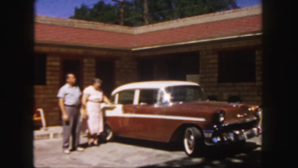 The woman reaches for the door of a two-tone station wagon while the man stands beside her at a Colorado motel in 1958.