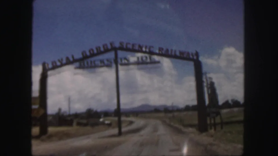 Close 8mm view of the Royal Gorge Scenic Railway entrance arch from a moving car in Colorado.