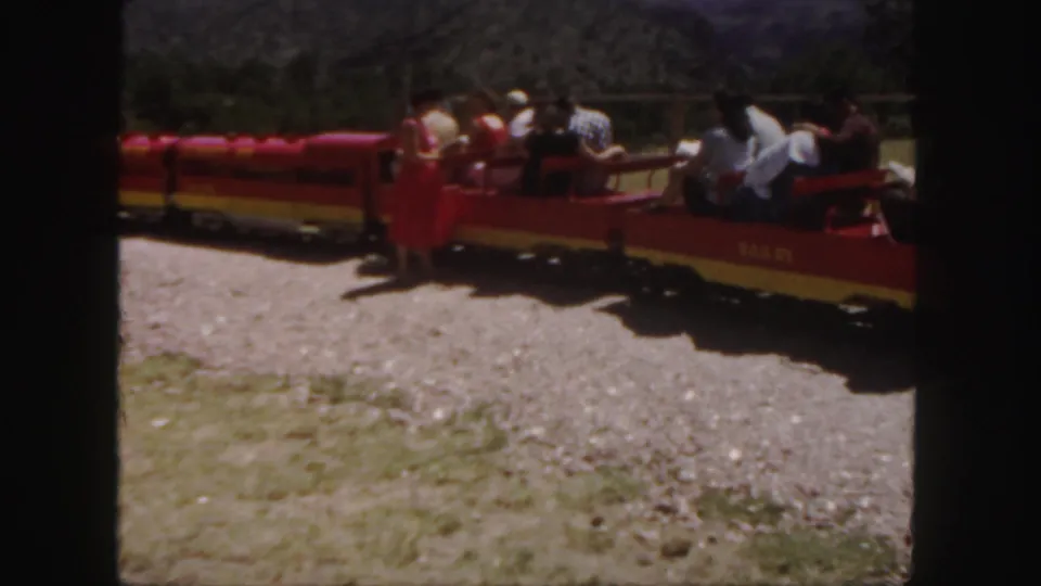 Close home-movie view of red and yellow train cars carrying passengers at a Colorado scenic attraction in 1958.