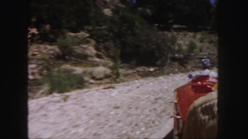 The passenger view continues from the red train car as the track curves through rocky Colorado terrain.