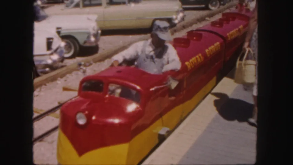Colorado home-movie frame of a Royal Gorge miniature train at a small amusement stop with riders and nearby walkway.