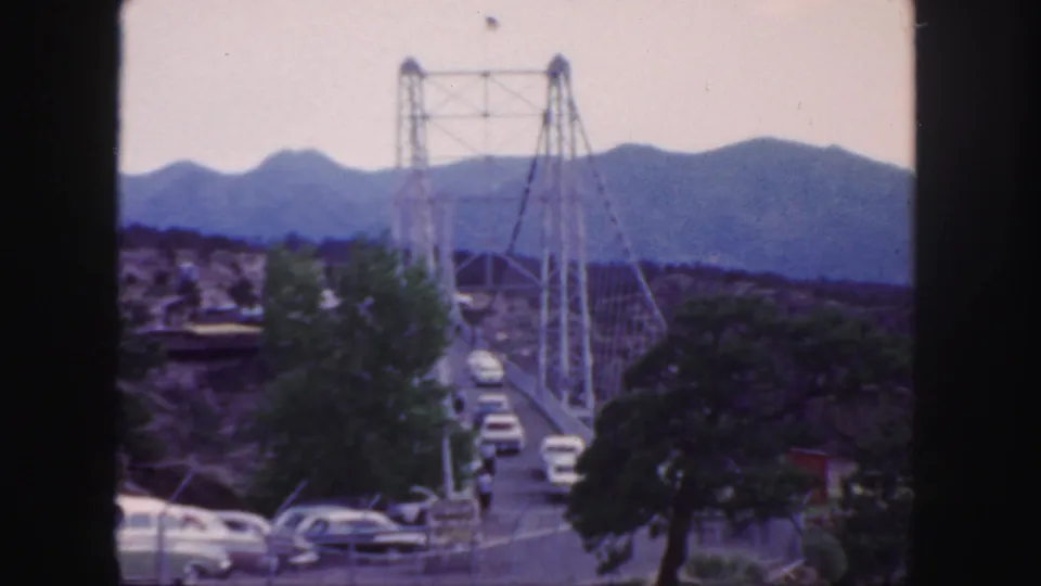 1958 Colorado home-movie view of a suspension bridge carrying classic cars through a mountain landscape.