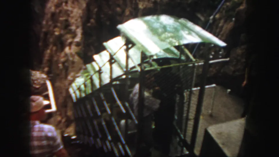 A closer 8mm view shows the rail bus roof, side railings, and passengers as the vehicle climbs the mountain track.