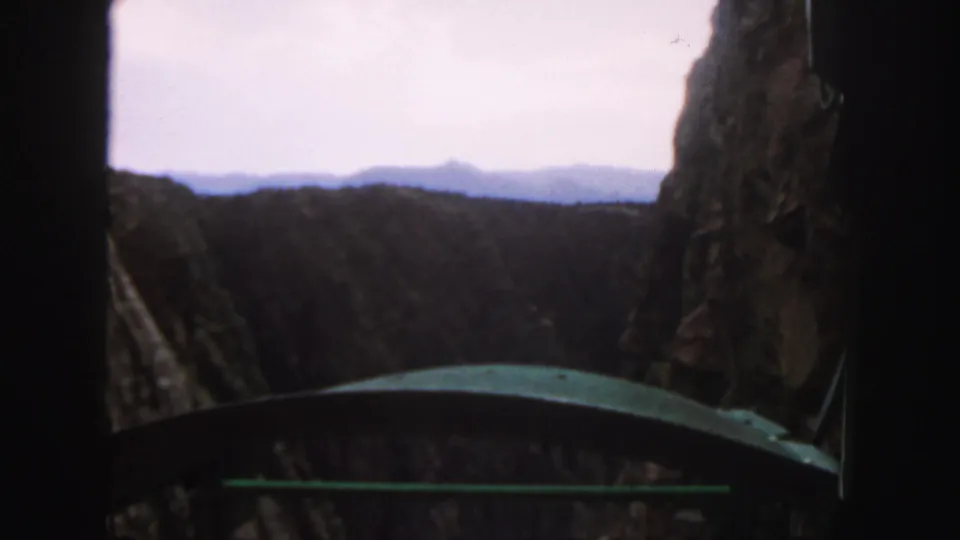 Colorado 1958 8mm frame showing close rock walls and a canyon vista from a passenger viewpoint.