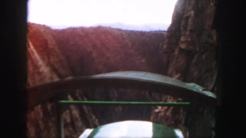 1958 Colorado 8mm view from inside a green mountain railway car, looking toward cliffs and track through a canyon.