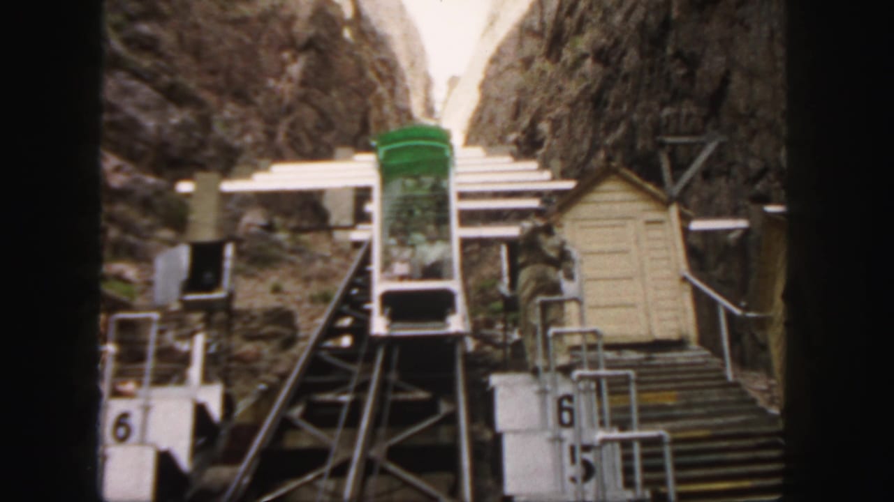 Green funicular car beside steep rails and a small shed in a rocky mountain pass.